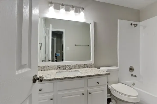 a bathroom with a granite countertop sink a toilet and a mirror
