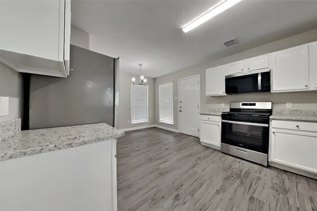 a kitchen with granite countertop a refrigerator and a stove top oven