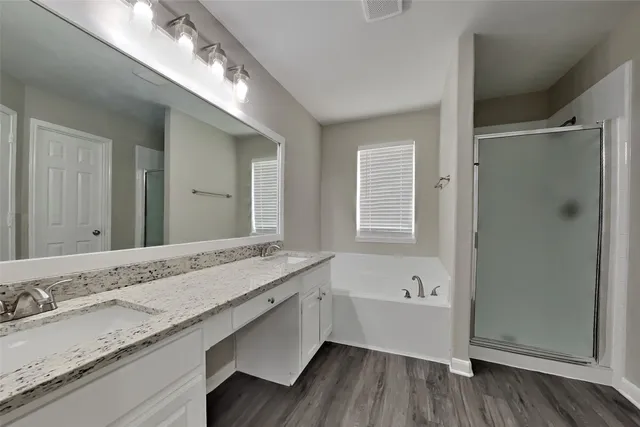 a bathroom with a granite countertop double vanity sink a mirror and bathtub