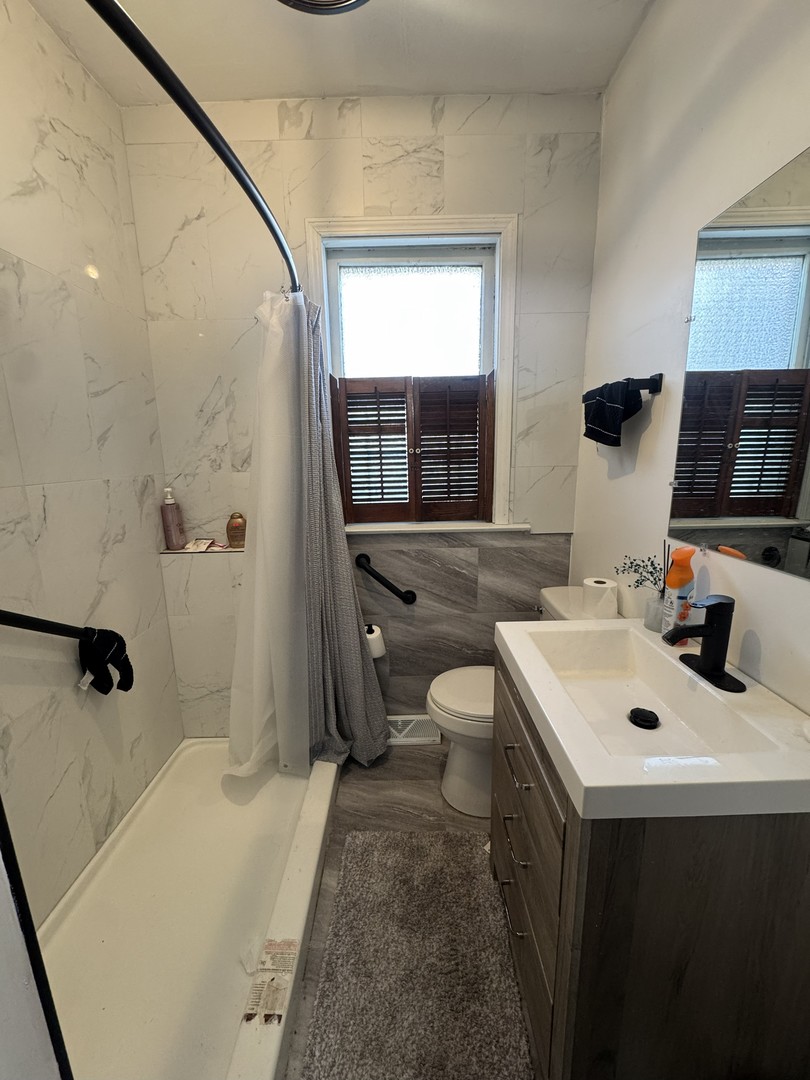 8239 South Ridgeland Avenue Chicago, IL 60617 - Photo 10 of 16 a bathroom with a sink a toilet a mirror and shower