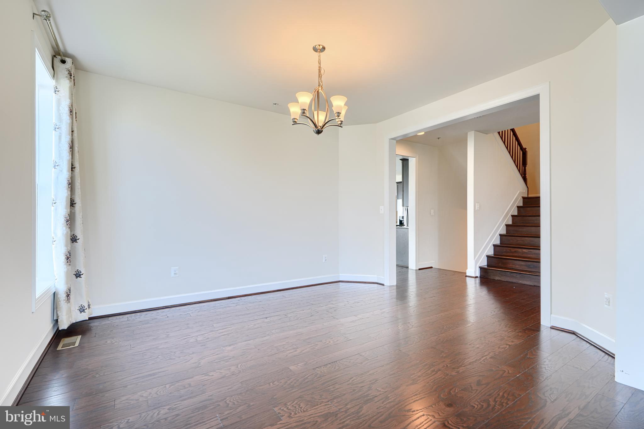 10819 White Trillium Road Perry Hall, MD 21128 - Photo 9 of 47 an empty room with wooden floor staircase and windows