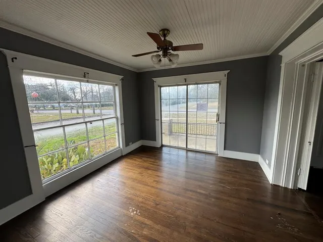 an empty room with wooden floor fan and windows