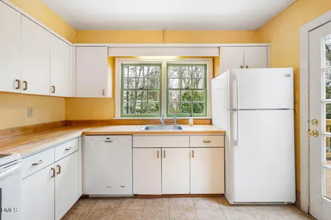 a view of a kitchen with white cabinets and a window