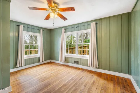 a view of an empty room with window and wooden floor