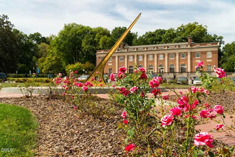 a view of a house with fountain and a flower garden