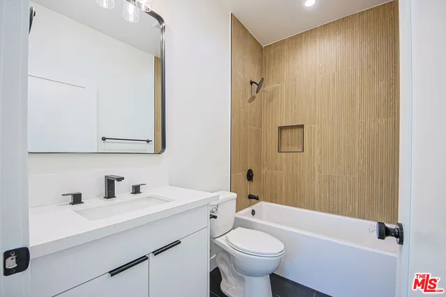 a kitchen with stainless steel appliances kitchen island granite countertop a refrigerator a stove a sink and a dining table with wooden floor