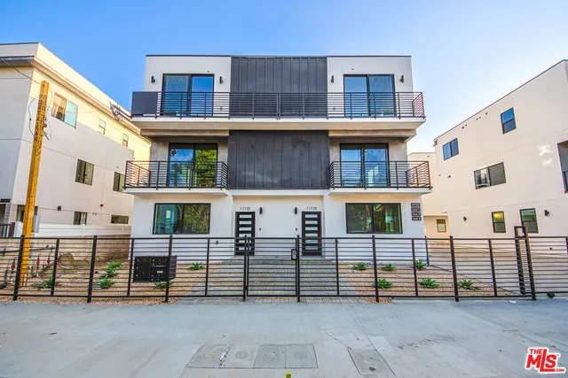 a view of a white building among the street with houses