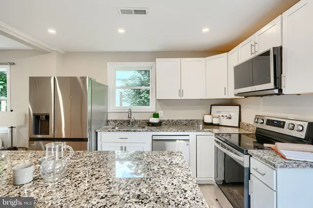 a kitchen with stainless steel appliances granite countertop a stove top oven a sink dishwasher a refrigerator and cabinets with wooden floor