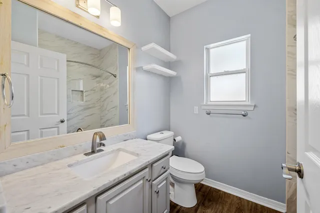 a bathroom with a granite countertop toilet sink and mirror