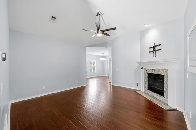 an empty room with wooden floor fireplace and windows