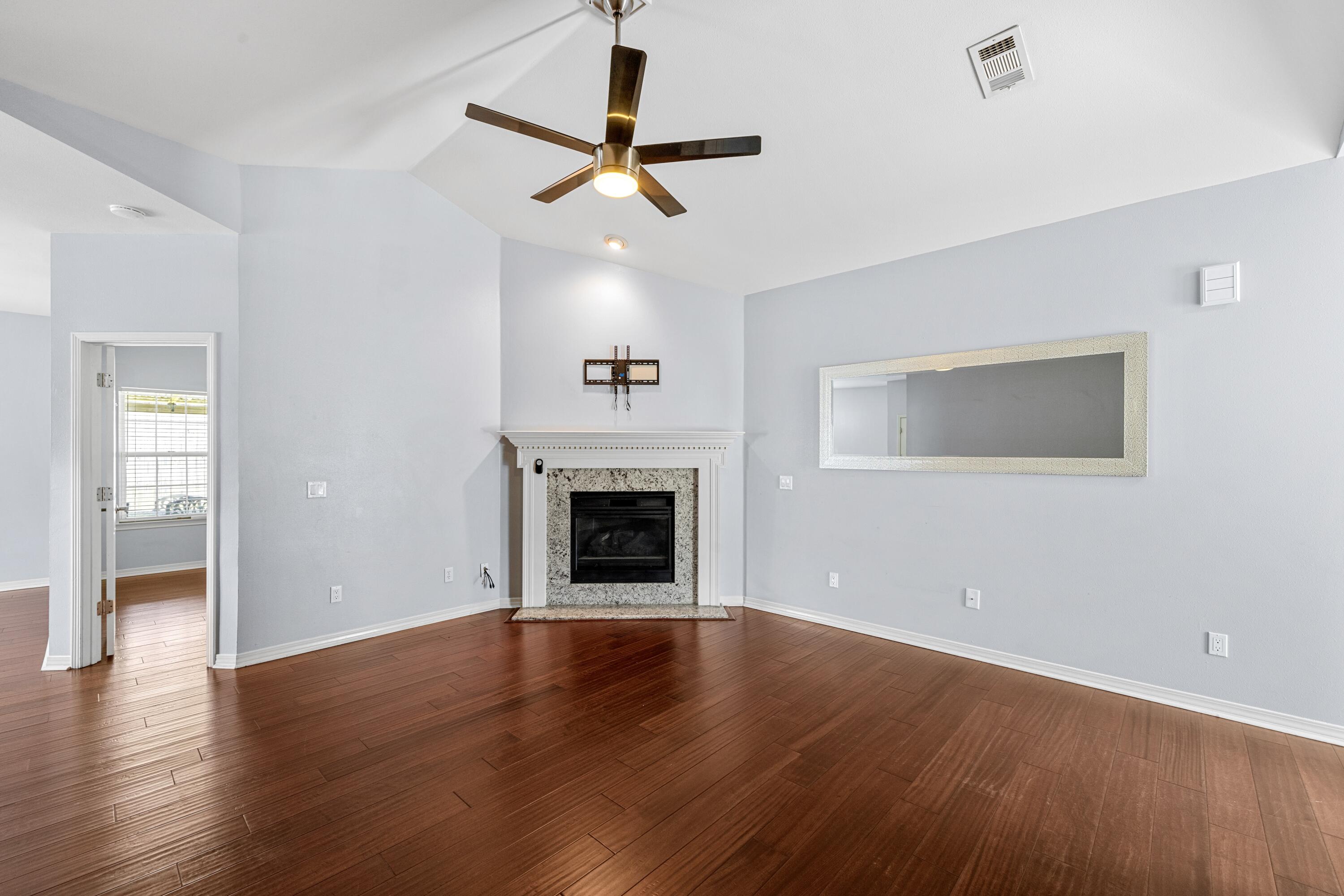 96 Trista Terrace Court Destin, FL 32541 - Photo 7 of 36 an empty room with wooden floor fireplace and windows
