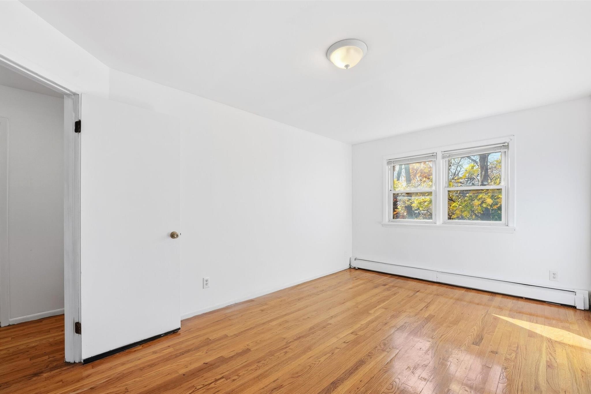 41 Alan Terrace, Unit 1 Jersey City, NJ 07306 - Photo 2 of 16 a view of an empty room with wooden floor and a window