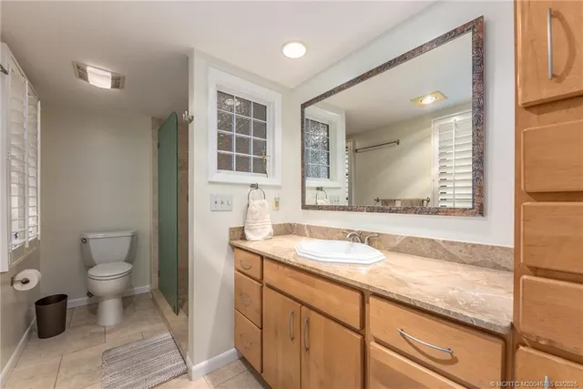 a bathroom with a granite countertop sink mirror vanity and toilet