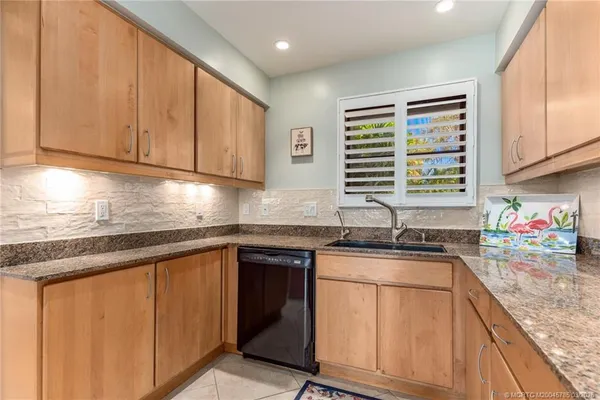 a kitchen with stainless steel appliances granite countertop wooden cabinets a sink and dishwasher next to a window