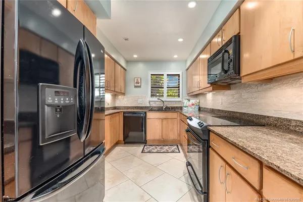 a kitchen with granite countertop a refrigerator stove and sink