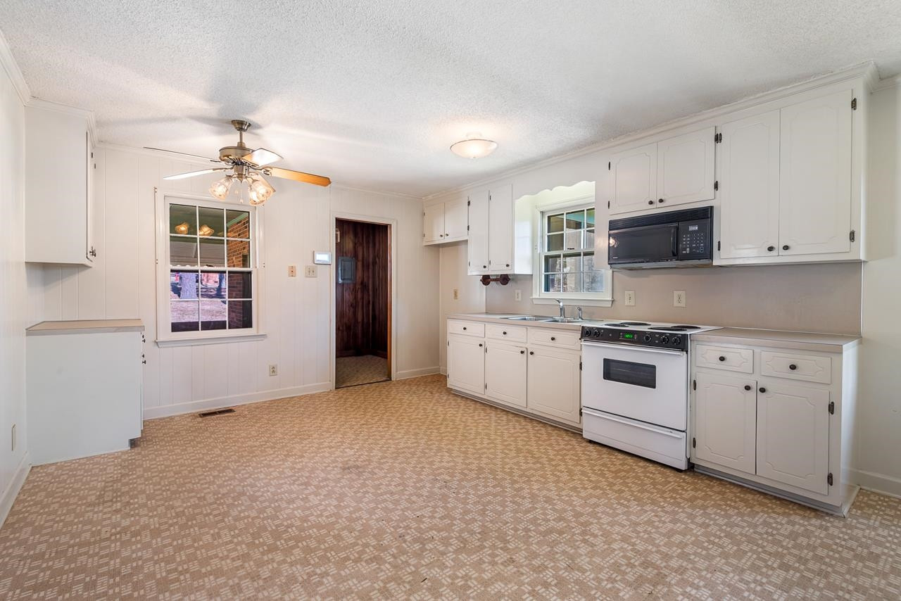 7222 Russell Road Durham, NC 27712 - Photo 19 of 38 a kitchen with stainless steel appliances white cabinets and window