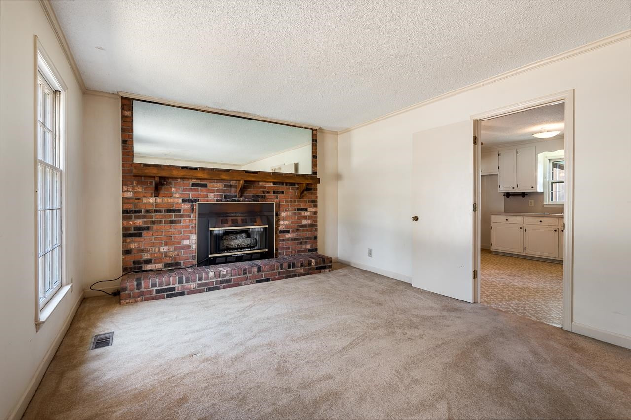 7222 Russell Road Durham, NC 27712 - Photo 6 of 38 an empty room with a fireplace and cabinet