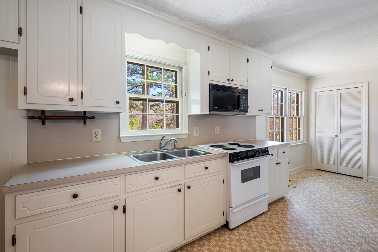 7222 Russell Road Durham, NC 27712 - Photo 7 of 38 a kitchen with granite countertop a stove a sink and a microwave