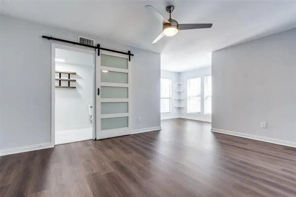 an empty room with wooden floor closet and windows