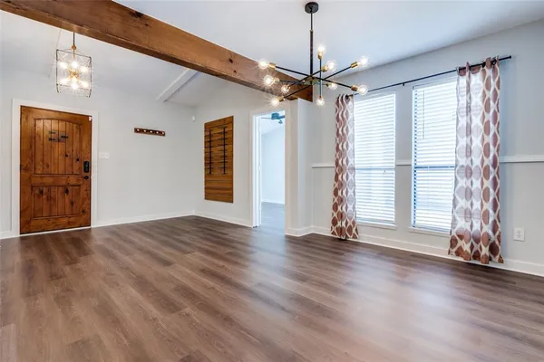 a view of an empty room with wooden floor ceiling fan and windows