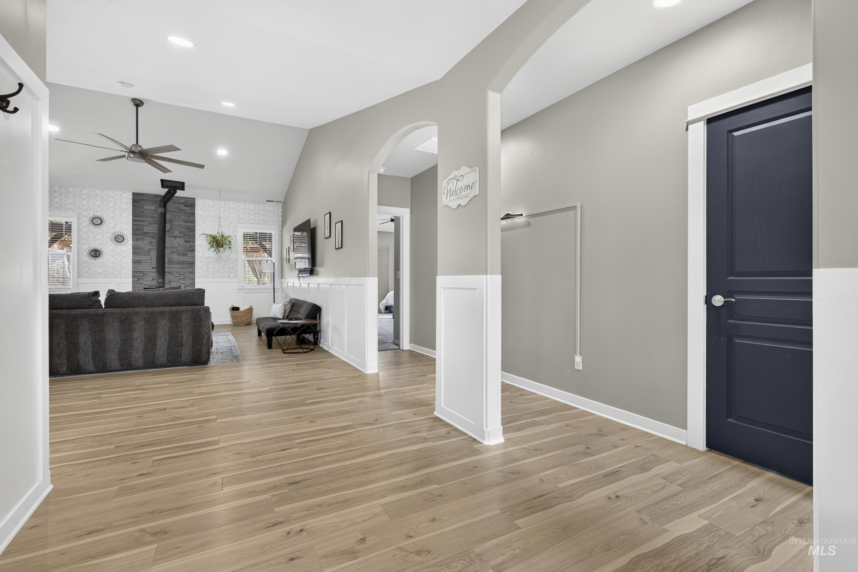 132 Mores Creek Rim Road Boise, ID 83716 - Photo 5 of 44 Vaulted ceiling, wood-finish flooring, accent wall with mosaic tile and dark paneling, arched hallway entry, and board and batten wainscoting