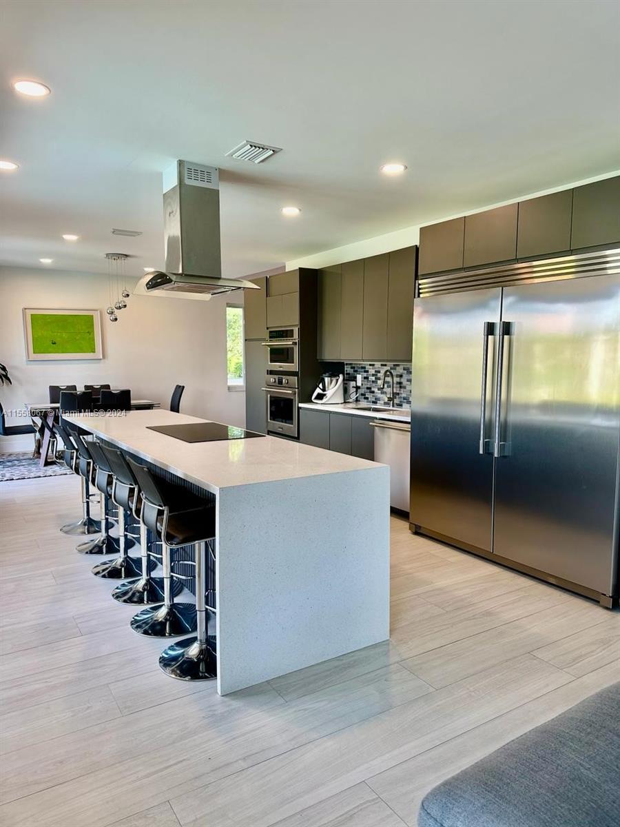 a large kitchen with stainless steel appliances a large counter top a stove and a refrigerator