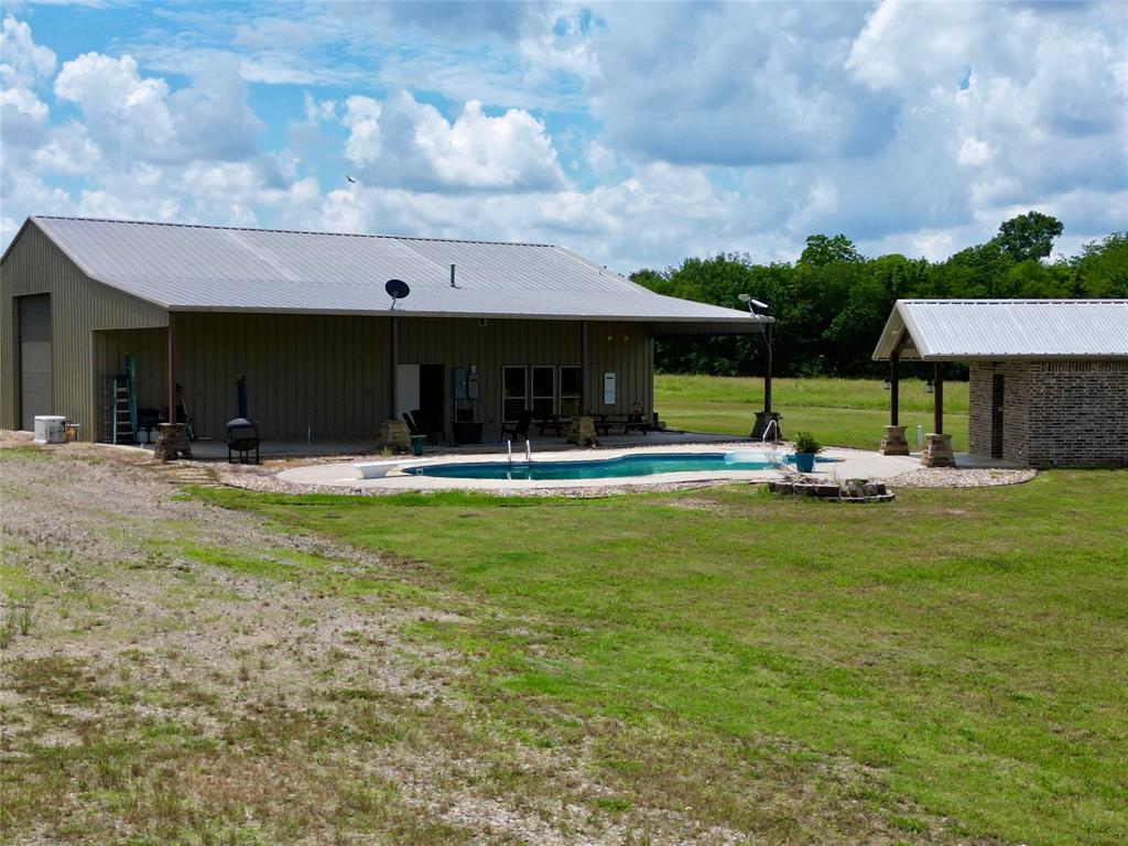 1524 County Road Sumner, TX 75486 - Photo 9 of 35 Property featuring an oval-shaped pool with surrounding concrete patio, 20x60 covered back patio with plumbing for outdoor kitchen