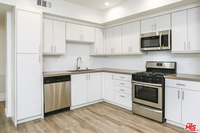 a kitchen with stainless steel appliances granite countertop a stove a sink and a microwave
