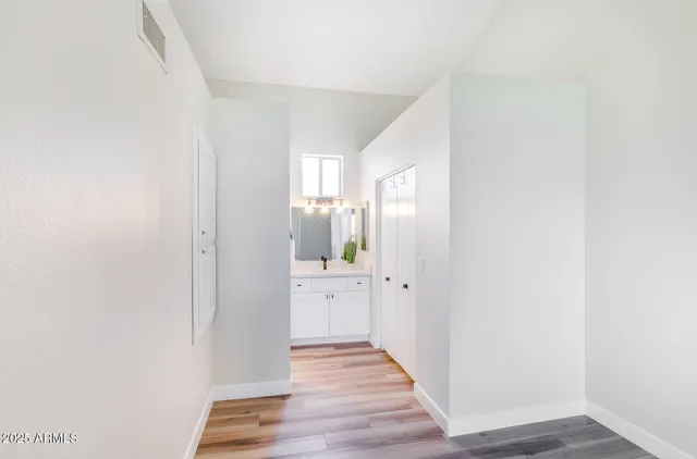 a view of a hallway with wooden floor and a bathroom