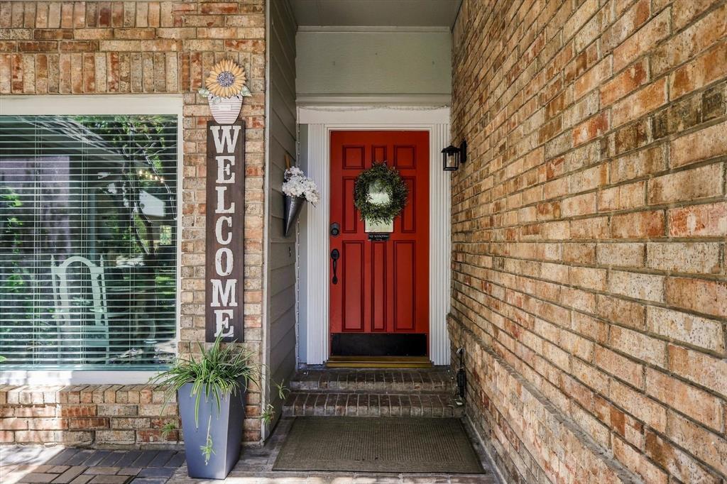 524 Post Oak Road Grapevine, TX 76051 - Photo 2 of 37 Brick exterior featuring a red entry door with white trim and a black wall-mounted light fixture