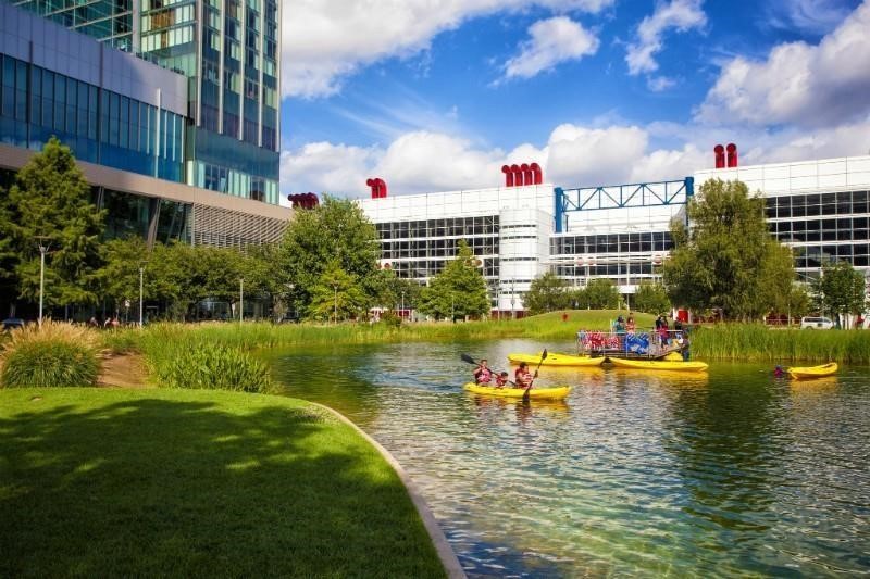 710 Delano Street, Unit A Houston, TX 77003 - Photo 32 of 32 Discovery Green showcases a modern cityscape with a scenic pond where people are kayaking. Surrounded by lush greenery and contemporary buildings, it offers a blend of urban living and outdoor recreation.