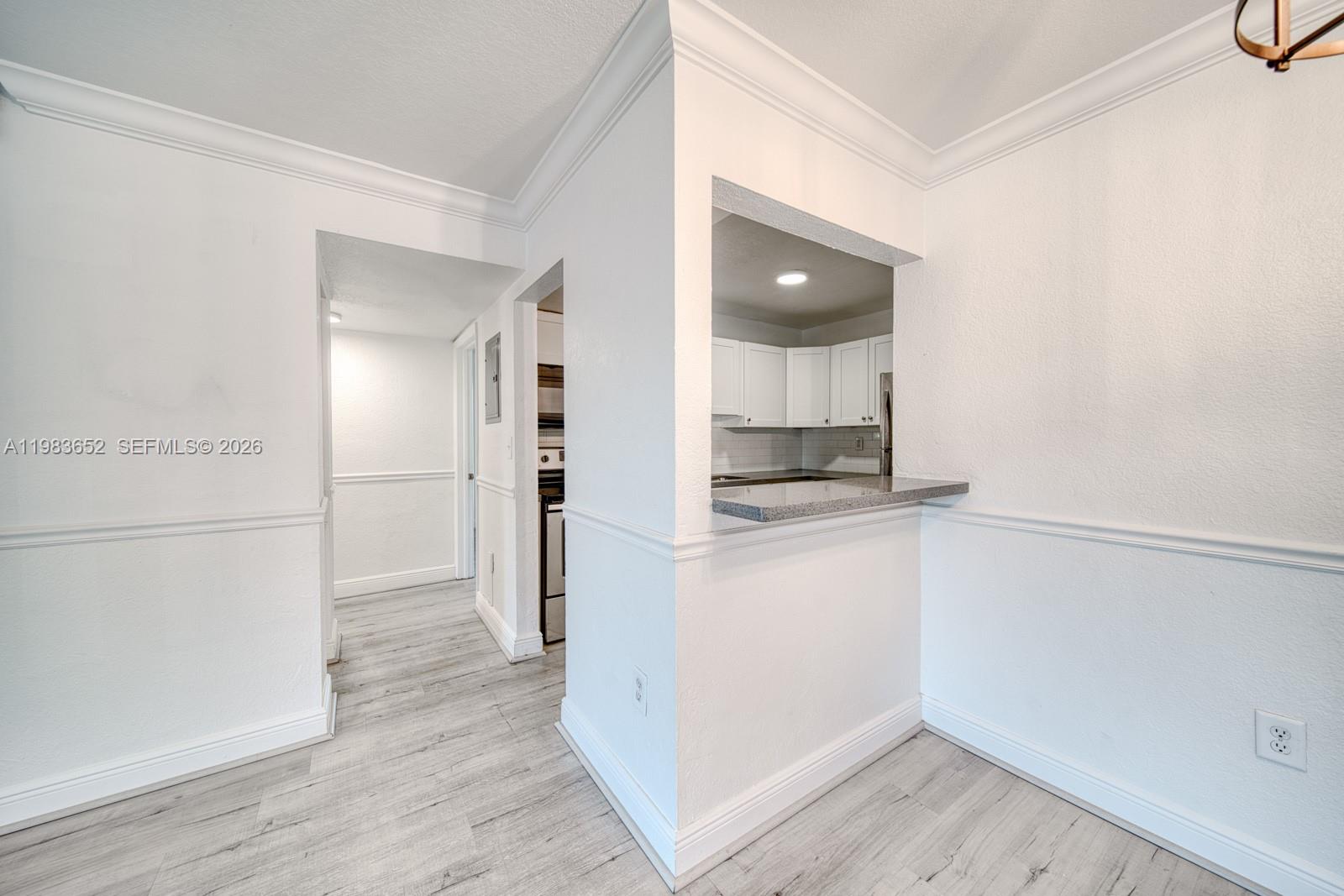 9459 Southwest 76th Street, Unit R5 Miami, FL 33173 - Photo 6 of 33 an empty room with wooden floor and kitchen