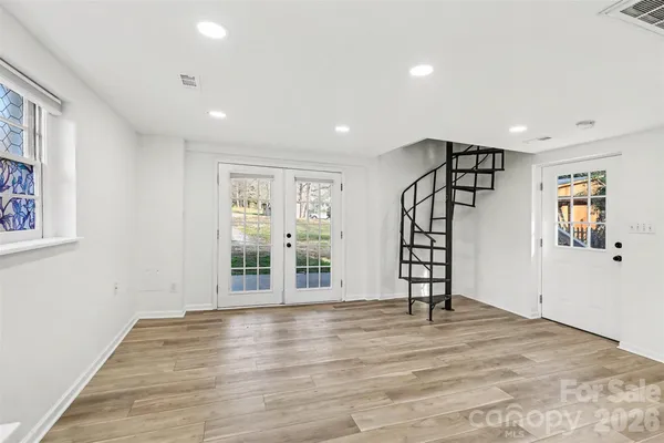 a view of an empty room with window and wooden floor