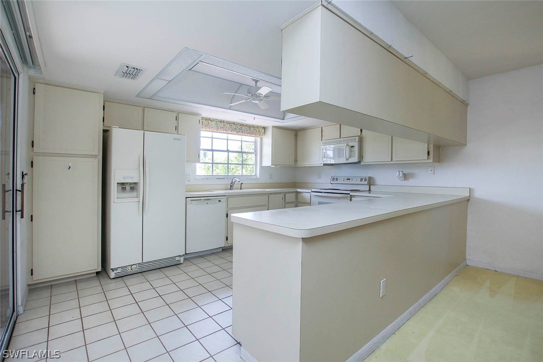 1573 Sand Castle Road Sanibel, FL 33957 - Photo 19 of 31 a kitchen with a sink a refrigerator and cabinets