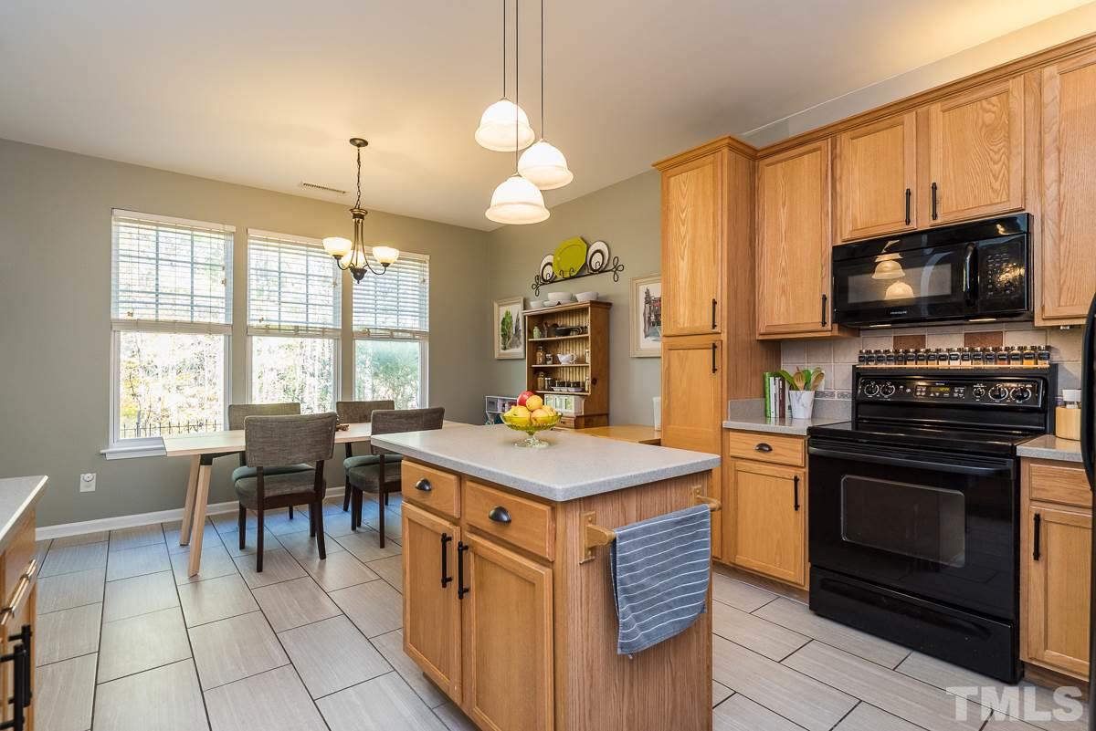 8516 Slabstone Court Raleigh, NC 27613 - Photo 3 of 30 a kitchen with a stove a sink a dining table and chairs