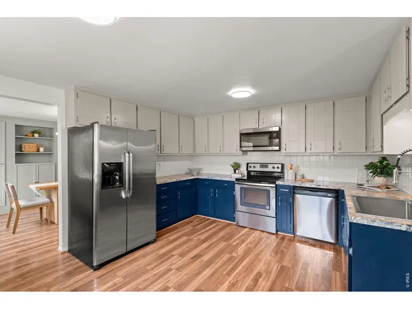 a kitchen with stainless steel appliances granite countertop a refrigerator a sink dishwasher a stove with wooden cabinets and floors