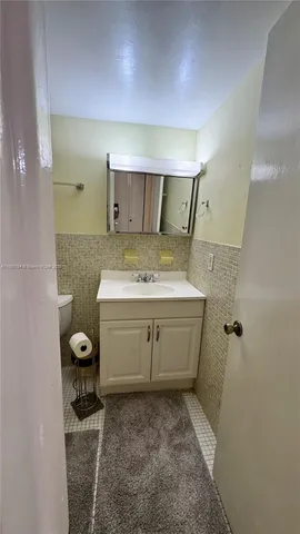 a bathroom with a granite countertop sink a toilet and mirror