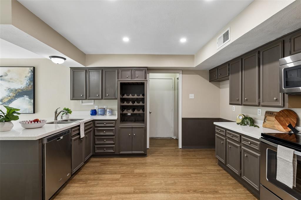 4962 Thunder Road Dallas, TX 75244 - Photo 6 of 26 Kitchen featuring wood-finish flooring, white quartz countertops, lots of cabinetry with brushed nickel hardware, and stainless steel appliances