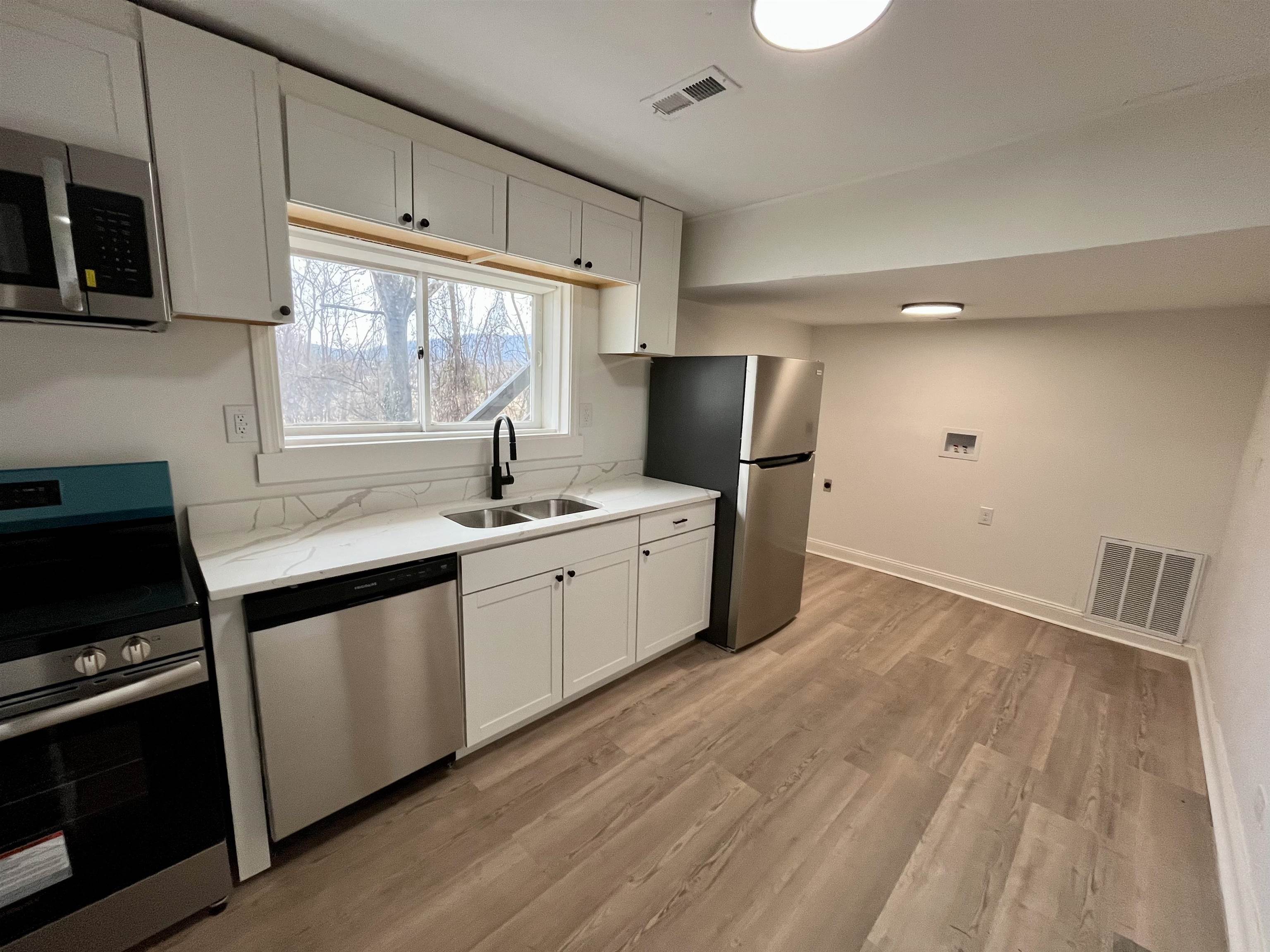 500 Ridge Street, Unit B Charlottesville, VA 22902 - Photo 6 of 13 a kitchen with stainless steel appliances white cabinets a sink a stove a refrigerator and microwave