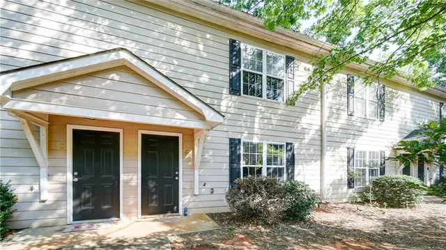 a view of a house with a yard and lawn chairs under an umbrella