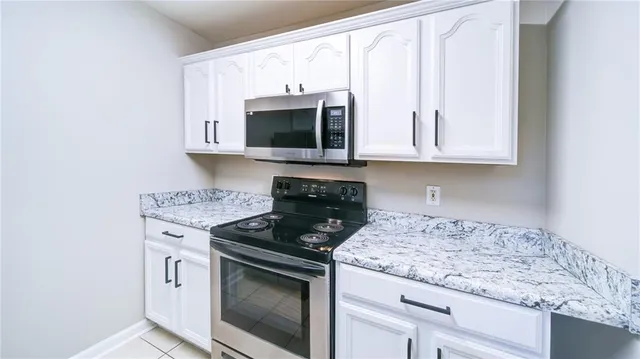 a kitchen with granite countertop white cabinets stainless steel appliances and a sink