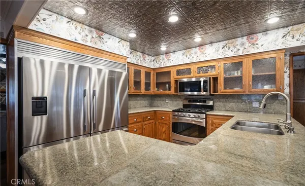a kitchen with stainless steel appliances granite countertop a refrigerator a stove and a sink with wooden floor
