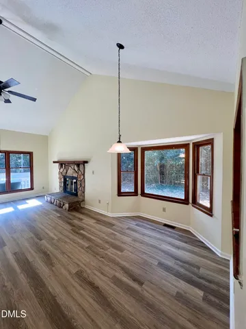 a view of an empty room with window and wooden floor