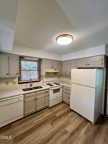 a kitchen with a sink white cabinets and white appliances