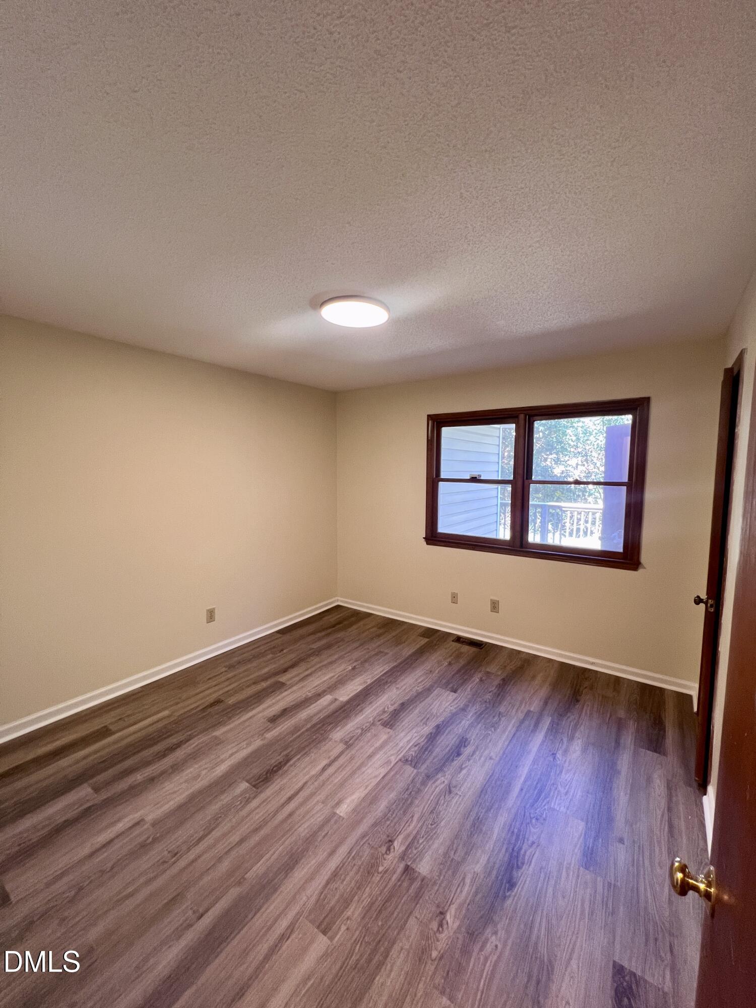 5132 Vann Street, Unit B Raleigh, NC 27606 - Photo 5 of 9 a view of an empty room with wooden floor and a window