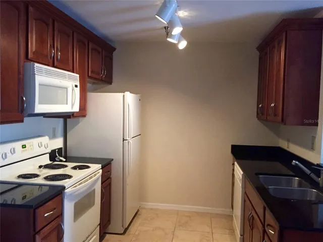 a kitchen with stainless steel appliances granite countertop a refrigerator a stove a sink a microwave and wooden floor