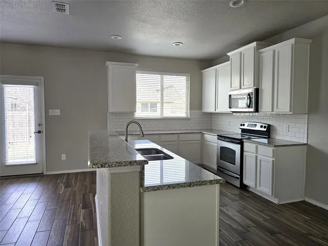 a kitchen with granite countertop a sink wooden floor and stainless steel appliances