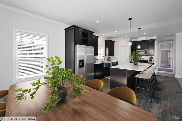 a kitchen with stainless steel appliances a dining table chairs stove refrigerator and cabinets