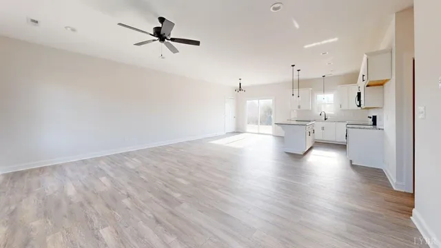 an empty room with wooden floor fan and windows