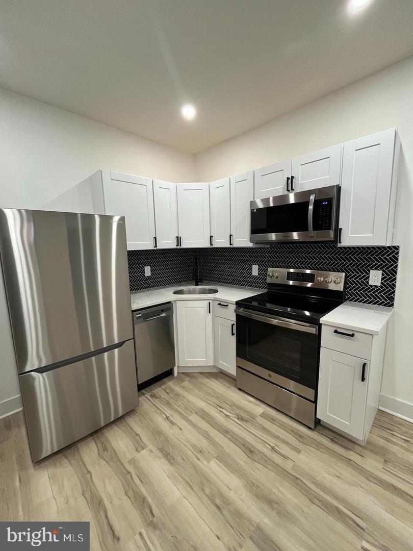 4817 North 15th Street Philadelphia, PA 19141 - Photo 4 of 10 a kitchen with granite countertop a refrigerator stove and white cabinets